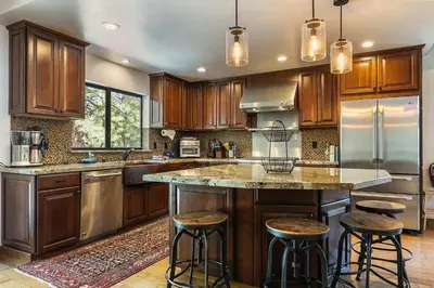 a kitchen with wooden cabinets and a large island with bar stools at Northstar Family Retreat on Shuttle Line with Deck in Truckee