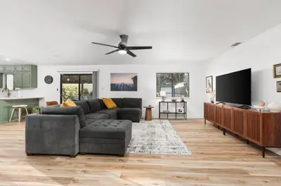 a living room with a couch and a flat screen tv at Stunning views with pool, spa, gold panning, firepit, game court and BBQ in Ahwahnee
