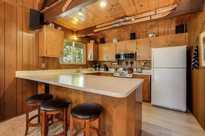 a kitchen with wooden walls and a white refrigerator at Arnold Chalet Near Town and Calaveras Big Trees! in Arnold