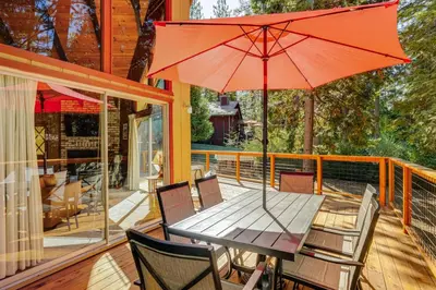 a table and chairs with an umbrella on a deck at Arnold Chalet Near Town and Calaveras Big Trees! in Arnold