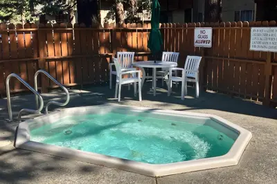 a hot tub in the ground with chairs and a table at La Residence M9 in Mammoth Lakes