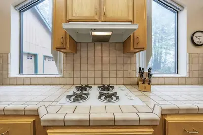a kitchen with a stove and two windows at Granite Ridge Getaway Chill Deck Vibes AC in Shaver Lake