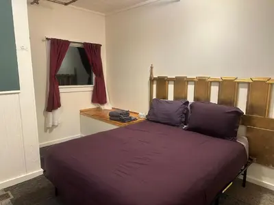 a bedroom with a bed with purple sheets and a window at West River House in Truckee