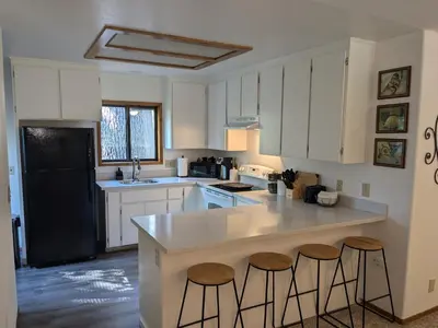 a kitchen with white cabinets and a black refrigerator at Bulldog Den in Twain Harte
