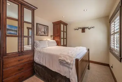 a bedroom with a bed with a wooden cabinet and windows at Luxury 3 BDR Northstar Condo in Truckee