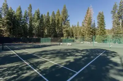 a tennis court with trees in the background at Luxury 3 BDR Northstar Condo in Truckee