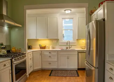a kitchen with white cabinets and a stainless steel refrigerator at Yosomite Gateway Historic Victorian with Modern Touch in Sonora