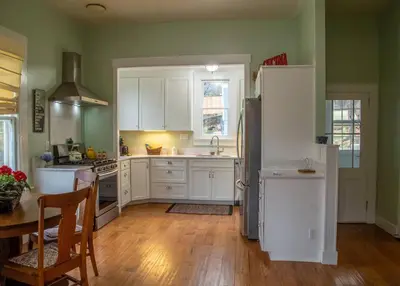 a kitchen with white cabinets and a table and a refrigerator at Yosomite Gateway Historic Victorian with Modern Touch in Sonora