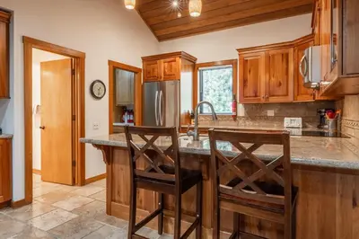 a kitchen with wooden cabinets and a stainless steel refrigerator at Snowcreek #482 - Updated ! 3 Bedroom + Loft, 2 Bathroom, Sleeps 10! in Mammoth Lakes