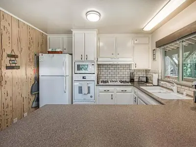 a kitchen with white cabinets and a white refrigerator at Elderberry Bluejay Location Goals Tub Time in Shaver Lake