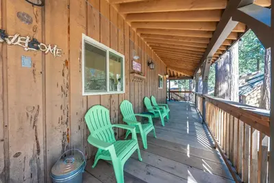 a row of green chairs on the porch of a cabin at Elderberry Bluejay Location Goals Tub Time in Shaver Lake