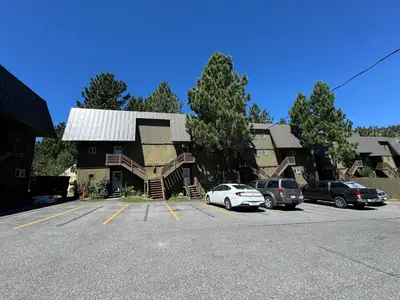 a building with cars parked in a parking lot at Cozy Condo in Mammoth with 2 parking spots! Ski,Snowboard, Ice skate! in Mammoth Lakes