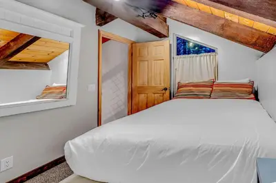 a bedroom with a white bed and a wooden door at Tahoe Condo Near Skylandia Beach in Tahoe City