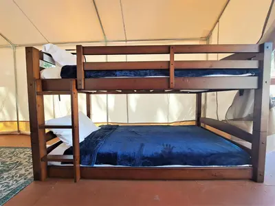 two bunk beds in a room with a blue bed at Wildhaven Yosemite Glamping in Mariposa