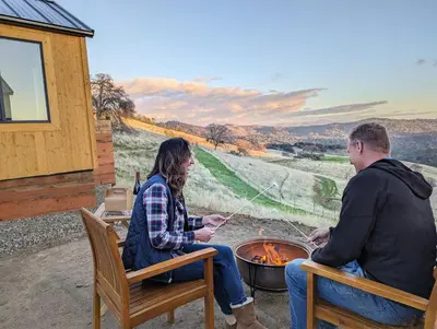 a man and a woman sitting around a fire at Wildhaven Yosemite Glamping in Mariposa