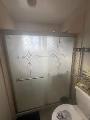a glass shower door in a bathroom with a toilet at Casa Pura Vida in Modesto