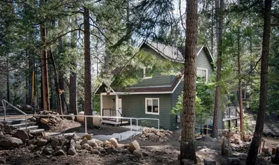 a small green house in the middle of a forest at 11N Margaret in North Wawona