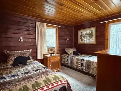 a bedroom with two beds and a cat laying on the bed at 10 Little Cabin In The Woods in North Wawona