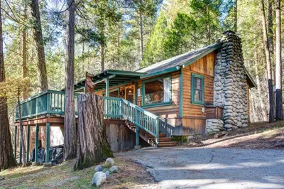 a log cabin in the woods with a wrap around porch at 10 Little Cabin In The Woods in North Wawona