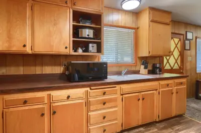 a kitchen with wooden cabinets and a sink and a microwave at 17C The Redwoods Cabin in North Wawona