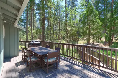a wooden deck with a table and chairs on it at 17C The Redwoods Cabin in North Wawona