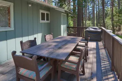 a wooden table and chairs on a deck at 17C The Redwoods Cabin in North Wawona