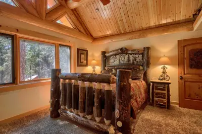 a bedroom with a wooden bed in a room with windows at Yosemite's Luxury Estate in North Wawona