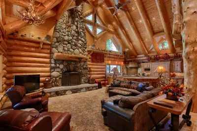 a living room with a stone fireplace in a log cabin at Yosemite's Luxury Estate in North Wawona