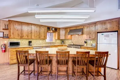 a kitchen with wooden cabinets and a large table with chairs at Riverfront Retreat in North Wawona