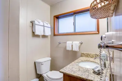 a bathroom with a toilet and a sink and a window at Riverfront Retreat in North Wawona