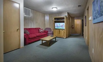 a living room with a red couch and a tv at Riverfront Retreat in North Wawona