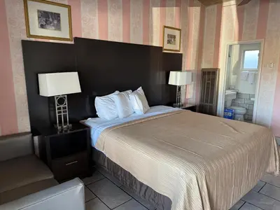 a bedroom with a large bed with two lamps at Cinderella Motel in Hollister