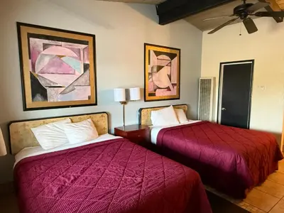 a hotel room with two beds and paintings on the wall at Cinderella Motel in Hollister
