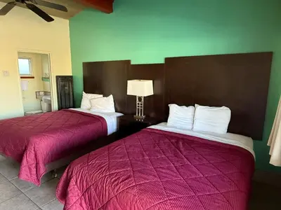 two beds in a hotel room with pink sheets at Cinderella Motel in Hollister