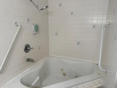 a white bath tub in a white tiled bathroom at Cinderella Motel in Hollister