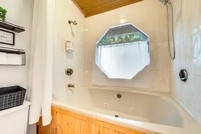 a bathroom with a bath tub and a window at Fire Pit, Gazebo and Grill Family Cabin in Arnold! in Arnold