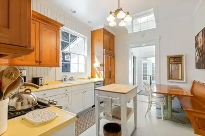a kitchen with white cabinets and a table and a counter at Belleview Lakefront by Tahoe Getaways - Hot Tub, Pier, Buoy and Guest House in Homewood