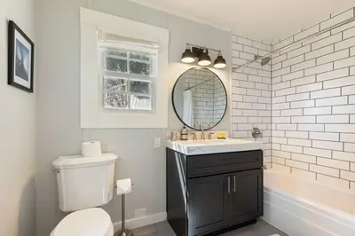 a bathroom with a toilet and a sink and a mirror at Belleview Lakefront by Tahoe Getaways - Hot Tub, Pier, Buoy and Guest House in Homewood