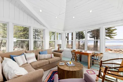 a living room with a couch and a table and windows at Belleview Lakefront by Tahoe Getaways - Hot Tub, Pier, Buoy and Guest House in Homewood
