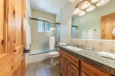 a bathroom with a toilet and a sink and a mirror at Eagle Rock By Tahoe Getaways - 4BR West Shore w Hot Tub & Close to Hiking! in Homewood