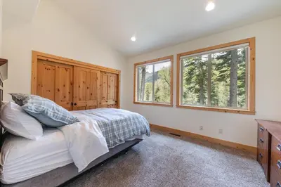 a bedroom with a bed and two windows at Eagle Rock By Tahoe Getaways - 4BR West Shore w Hot Tub & Close to Hiking! in Homewood