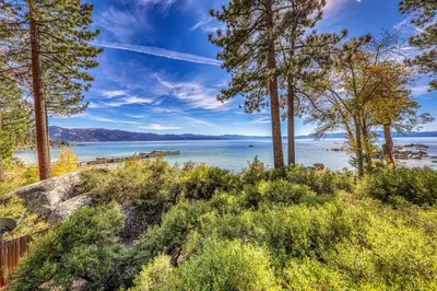 a view of a body of water with trees at Spellbound Lakefront Lodge by Tahoe Getaways - 5 BR w Hot Tub, Buoy & Beach access in Kings Beach