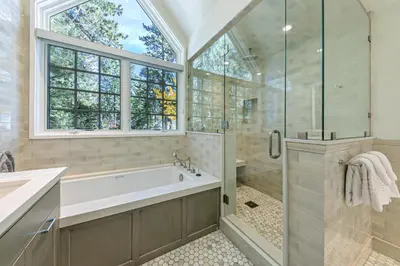 a bathroom with a tub and a shower with a window at Spellbound Lakefront Lodge by Tahoe Getaways - 5 BR w Hot Tub, Buoy & Beach access in Kings Beach