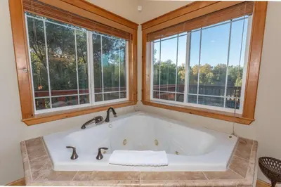 a large bath tub in a room with windows at Luxury Lodge-Hot Tub-BBQ-Sleeps 18 in Oakhurst