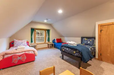 a attic bedroom with two beds and a window at Luxury Lodge-Hot Tub-BBQ-Sleeps 18 in Oakhurst