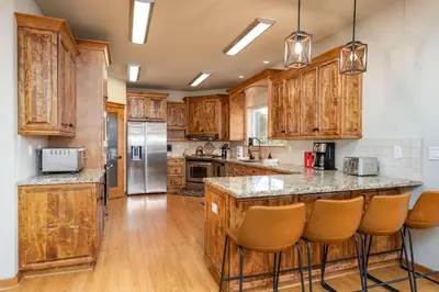 a kitchen with wooden cabinets and a island with bar stools at Luxury Lodge-Hot Tub-BBQ-Sleeps 18 in Oakhurst