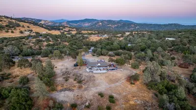 an aerial view of a house in the middle of a forest at 4000 SF, 20 Acre Gated Luxe Estate, Game Room, Pano View, Pool, Spa in Coarsegold