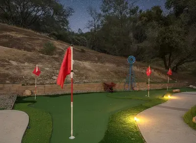 a miniature golf course with red flags on a green at Heaven Heights - HotTub, Pet Friendly, EV Outlet, Pool Table, Game Room, BBQ, FirePit, Library in Oakhurst
