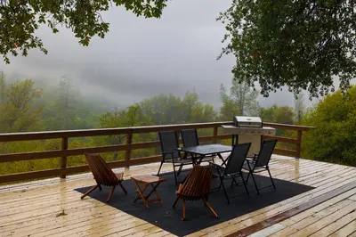 a patio with a table and chairs on a wooden deck at Sierra Vista Near Yosemite #Majestic Views# Tesla EV in Oakhurst