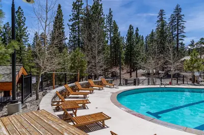 a pool with wooden benches and a row of tables and chairs at Updated Pet Friendly Monache Studio with Views! in Mammoth Lakes